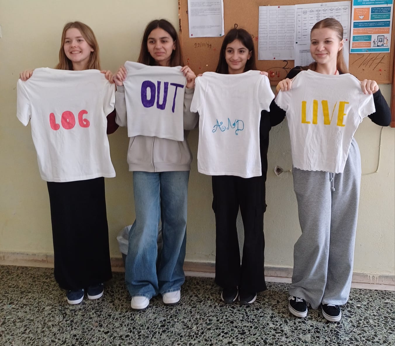 Cztery dziewczyny prezentują koszulki z napisem LOG OUT and LIVE